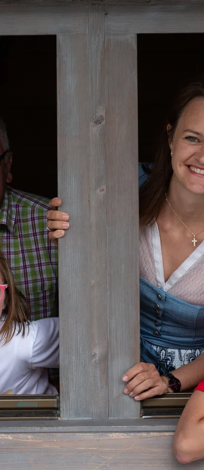 Smiling multigenerational family looking out of a wooden cabin window